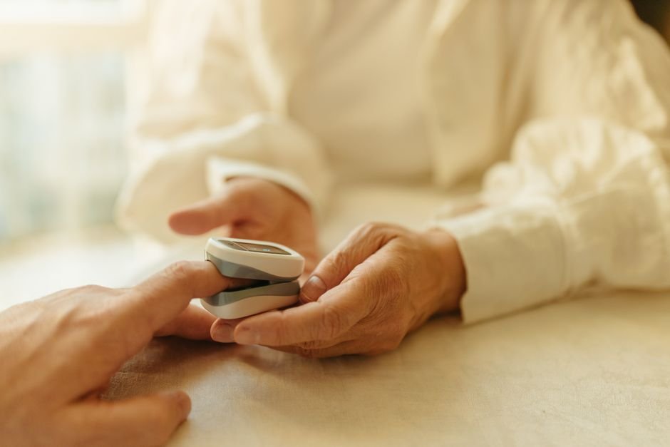 Close-up of a senior adult using a pulse oximeter for a health check indoors.